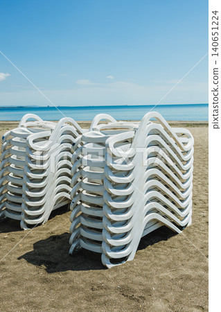 Beach chairs arranged. Calm ocean horizon with orderly outdoor seating sets. Relaxing beachfront scene showing symmetrical white chairs under vast sky before guests arrive Beach chairs arranged. Calm ocean horizon with orderly outdoor seating sets. Relaxing beachfront scene showing symmetrical white chairs under vast sky before guests arrive 140651224