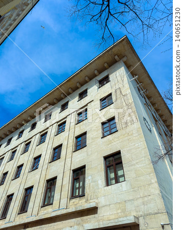 Building stands tall under clear blue sky with clouds passing by in urban area in a modern city during daytime 140651230