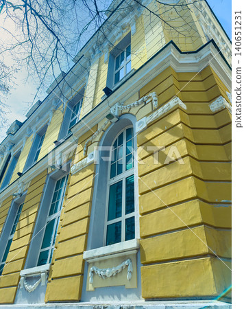 Bright yellow building with large windows and decorative elements in a city on a sunny day with clear sky Bright yellow building with large windows and decorative elements in a city on a sunny day with clear sky 140651231