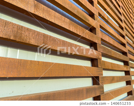 Wooden slats create a pattern in a modern architectural design located in an urban area during bright daylight hours Wooden slats create a pattern in a modern architectural design located in an urban area during bright daylight hours 140651233
