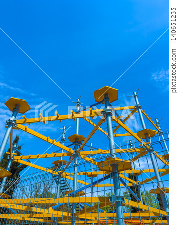 Construction site shows scaffolding under clear blue sky near a busy area in the afternoon with workers preparing for building tasks Construction site shows scaffolding under clear blue sky near a busy area in the afternoon with workers preparing for building tasks 140651235