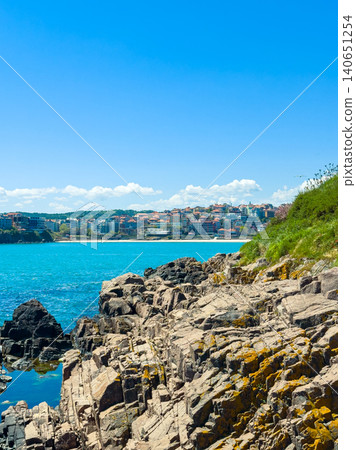 Coastal view of rocky shore with city skyline in the background during bright sunny day Coastal view of rocky shore with city skyline in the background during bright sunny day 140651254