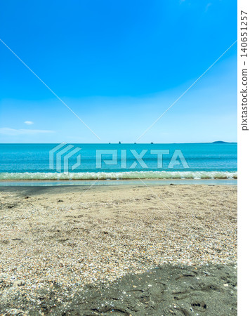 Clear blue water meets sandy beach with gentle waves under a sunny sky, in a coastal area during the afternoon Clear blue water meets sandy beach with gentle waves under a sunny sky, in a coastal area during the afternoon 140651257