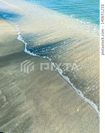 Waves gently wash up on a sandy beach during the afternoon sun near the ocean shoreline Waves gently wash up on a sandy beach during the afternoon sun near the ocean shoreline 140651258