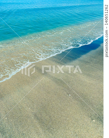 Waves wash onto sandy shore at clear ocean during bright sunny day at midday Waves wash onto sandy shore at clear ocean during bright sunny day at midday 140651262