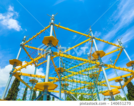 Climbing structure in a park on a sunny day with bright blue sky and white clouds Climbing structure in a park on a sunny day with bright blue sky and white clouds 140651270
