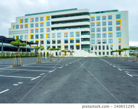 Modern building with a large parking lot in an urban area during a cloudy day Modern building with a large parking lot in an urban area during a cloudy day 140651295