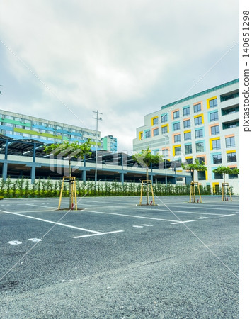 Empty parking lot with yellow poles and modern buildings in the background during daylight hours in an urban area Empty parking lot with yellow poles and modern buildings in the background during daylight hours in an urban area 140651298