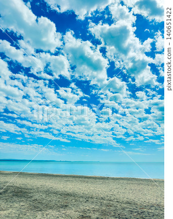Clouds cover the sky above the calm sea and sandy beach during a bright day near the coast, inviting visitors to enjoy the natural beauty Clouds cover the sky above the calm sea and sandy beach during a bright day near the coast, inviting visitors to enjoy the natural beauty 140651422