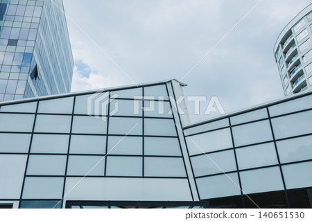 Modern architecture stands tall under a cloudy sky in a city center with glass facades reflecting urban life during the day Modern architecture stands tall under a cloudy sky in a city center with glass facades reflecting urban life during the day 140651530