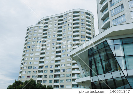 Tall apartment building in a city with a modern design near a cloudy sky during the day Tall apartment building in a city with a modern design near a cloudy sky during the day 140651547