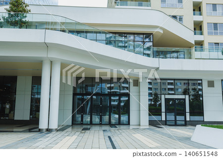 Modern building entrance with glass doors and clean lines in a busy urban area during daytime, showcasing the sleek design and architecture 140651548