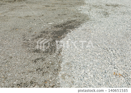 Gravel area shows wet and dry sections after rain in open space during the day 140651585