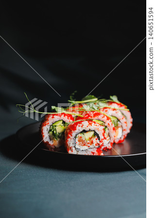 Sushi rolls sit on a black plate with green decorations in a dimly lit setting during a dinner event at a restaurant Sushi rolls sit on a black plate with green decorations in a dimly lit setting during a dinner event at a restaurant 140651594