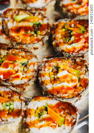 Creative sushi rolls arranged neatly on a plate with a drizzle of sauce at a local eatery during lunch hours Creative sushi rolls arranged neatly on a plate with a drizzle of sauce at a local eatery during lunch hours 140651605