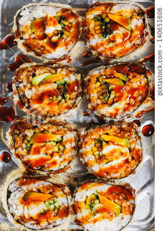 Fresh sushi rolls are served on a metal tray with sauce on top during dinner time at a local restaurant in the city Fresh sushi rolls are served on a metal tray with sauce on top during dinner time at a local restaurant in the city 140651606
