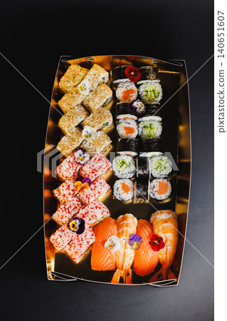 Variety of sushi displayed on a rectangular tray with different types and colors of sushi pieces arranged neatly Variety of sushi displayed on a rectangular tray with different types and colors of sushi pieces arranged neatly 140651607