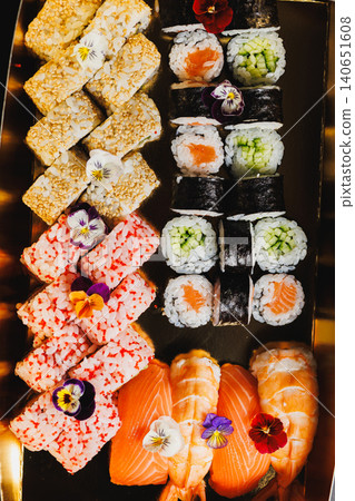 Sushi platter served on a golden tray featuring a variety of rolls and fish in a restaurant setting during dinner hours 140651608