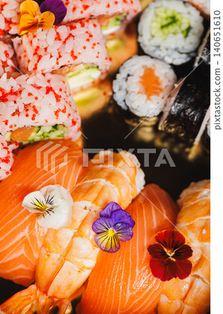 Sushi platter with salmon, colorful rolls, and edible flowers served on a plate during a dining experience 140651610