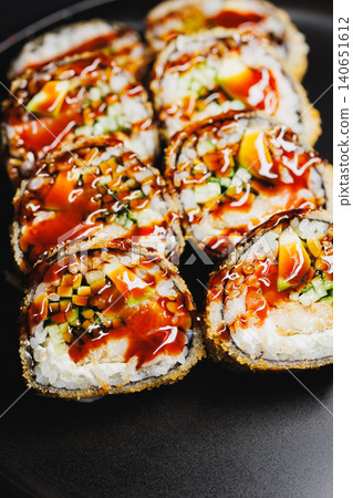 Sushi rolls with various ingredients on a black plate served at a restaurant during lunchtime for diners Sushi rolls with various ingredients on a black plate served at a restaurant during lunchtime for diners 140651612