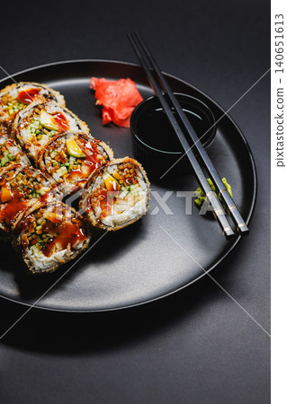 Sushi rolls served on a black plate with soy sauce, wasabi, and pickled ginger during a dinner time gathering Sushi rolls served on a black plate with soy sauce, wasabi, and pickled ginger during a dinner time gathering 140651613