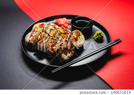 Sushi rolls served on a black plate with dipping sauce and garnishes at a restaurant during dinner time Sushi rolls served on a black plate with dipping sauce and garnishes at a restaurant during dinner time 140651619