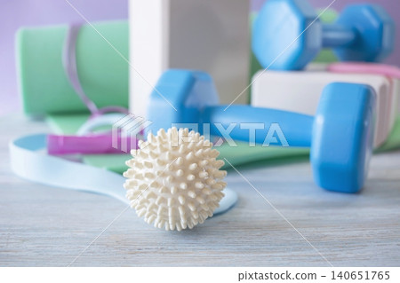 Fitness equipment for home workouts on a wooden floor. Fitness equipment with yoga mat, blocks, dumbbells and massage ball. Fitness equipment for home workouts on a wooden floor. Fitness equipment with yoga mat, blocks, dumbbells and massage ball. 140651765