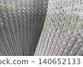 Featuring an intricate, fan-like geometry, the sculpture relies on a central, sinuous partition that gracefully divides the frame. Dozens of metallic, monochromatic ribs radiate outward from this 140652133