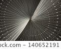 The composition is dominated by a sweeping arrangement of metallic, monochromatic ribs that converge and fan outward with the elegance of a bird wing. A prominent, twisting curve dramatically 140652191