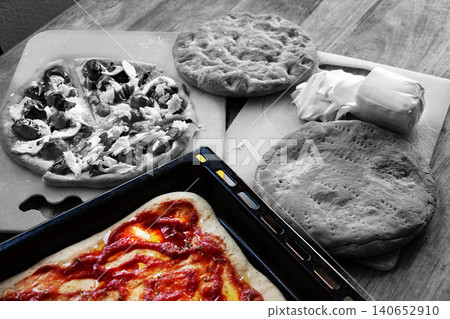 Homemade pizza preparation with fresh ingredients on wooden table Homemade pizza preparation with fresh ingredients on wooden table 140652910