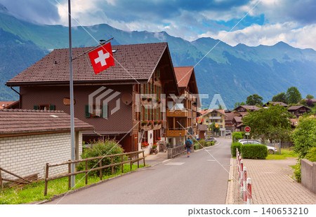 Traditional Swiss Chalets and National Flag in Iseltwald Switzerland Traditional Swiss Chalets and National Flag in Iseltwald Switzerland 140653210