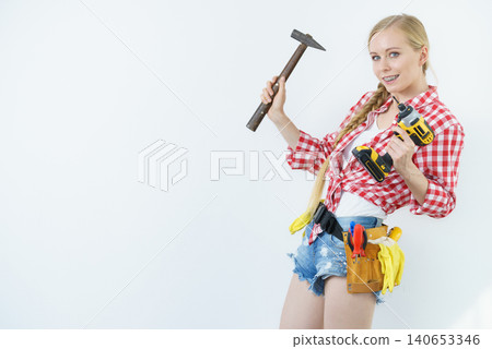 Handyman woman with hammer and drill 140653346