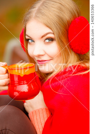 Girl in autumn park enjoying hot drink 140653366