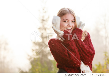 Portrait of pretty smiling woman in white earmuffs. 140653369