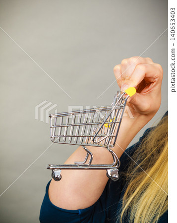 Woman hand holding small tiny shopping cart Woman hand holding small tiny shopping cart 140653403