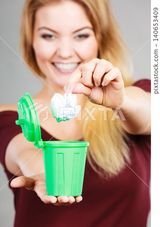 Woman putting paper into small trash can Woman putting paper into small trash can 140653409