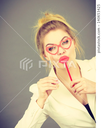 Happy elegant woman holding carnival accessoies on stick Happy elegant woman holding carnival accessoies on stick 140653425