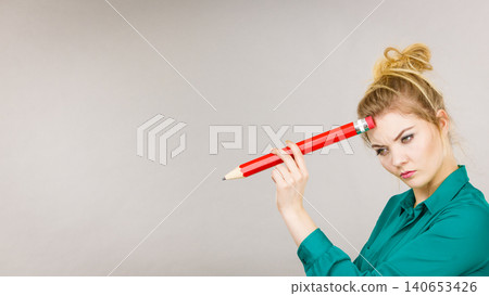 Woman confused thinking, big pencil in hand Woman confused thinking, big pencil in hand 140653426
