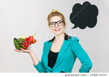 Woman holds shopping cart with vegetables, copy space 140653434