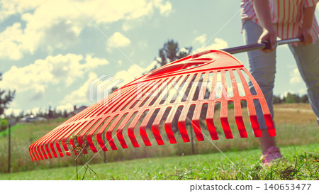 Unusual angle of woman raking leaves Unusual angle of woman raking leaves 140653477
