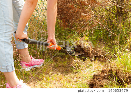 Woman digging hole in garden Woman digging hole in garden 140653479