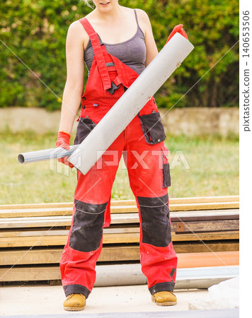 Woman carrying pipes on construction site Woman carrying pipes on construction site 140653506