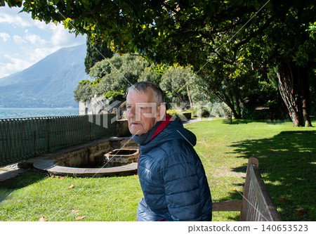 Elderly Man Sitting Alone on a Bench by Lake Como, Italy, Off-Season Elderly Man Sitting Alone on a Bench by Lake Como, Italy, Off-Season 140653523