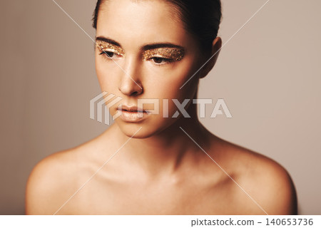 Woman, makeup and gold glitter eyeshadow for beauty, cosmetology and glamour with cosmetics on beige background. Sparkle, elegance and fashion model in studio, art or creativity with shimmer and glow Woman, makeup and gold glitter eyeshadow for beauty, cosmetology and glamour with cosmetics on beige background. Sparkle, elegance and fashion model in studio, art or creativity with shimmer and glow 140653736