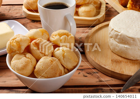 Traditional Brazilian breakfast with homemade cheese bread, fresh Minas cheese, black coffee, and corn and butter cake on a rustic table. Traditional Brazilian breakfast with homemade cheese bread, fresh Minas cheese, black coffee, and corn and butter cake on a rustic table. 140654011