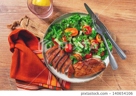 Delicious grilled duck breast served with fresh garden salad and cherry tomatoes at a rustic dining table Delicious grilled duck breast served with fresh garden salad and cherry tomatoes at a rustic dining table 140654106