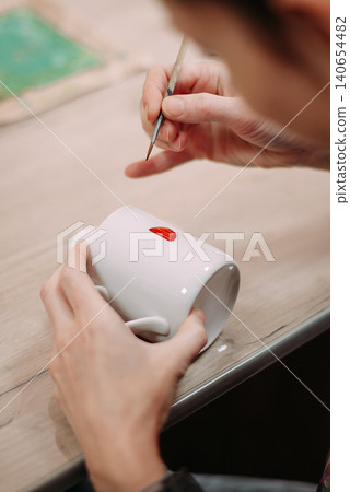 Man painting handmade ceramic cup at workshop Man painting handmade ceramic cup at workshop 140654482