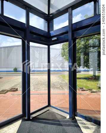 View from inside the building through a corner glass vestibule and automatic doors. 140655604