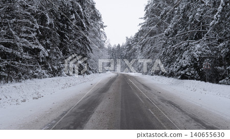 Icy Winter Road. Frozen Highway With Caution Advised. Slippery Winter Street With Snow And Ice Covering Pavement. Dark Rainy Road Lined With Snow And Ice During Cold Winter Nights Icy Winter Road. Frozen Highway With Caution Advised. Slippery Winter Street With Snow And Ice Covering Pavement. Dark Rainy Road Lined With Snow And Ice During Cold Winter Nights 140655630