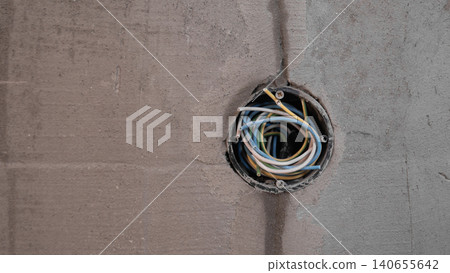 Exposed Multicolored Wires In Junction Box, Cables Looped Inside Circular Opening In Plaster Wall, Detailed View Of Insulated Conductors At Electrical Roughin Stage, Utilitarian Construction Exposed Multicolored Wires In Junction Box, Cables Looped Inside Circular Opening In Plaster Wall, Detailed View Of Insulated Conductors At Electrical Roughin Stage, Utilitarian Construction 140655642